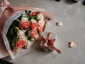 Букет коралових і кремових троянд поруч із подарунковою коробкою